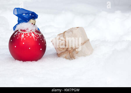 Red christmas Ball und Geschenk in Handwerk Papier auf Schnee. Weihnachten Hintergrund Stockfoto