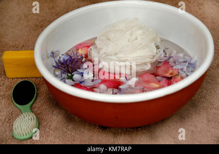 Schale mit Blütenblätter schweben im Wasser und Bad-Accessoires Stockfoto