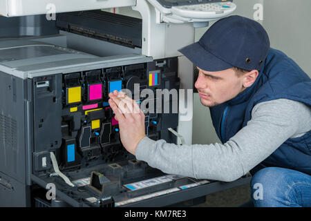junge männliche Techniker Reparatur digitaler Kopierer Drucker Maschine Stockfoto