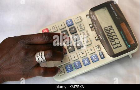 Afrikanerin, die Berechnungen auf einem Rechner Stockfoto