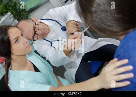 Arzt mit zungenspatel Kehle von Patienten zu untersuchen, Stockfoto
