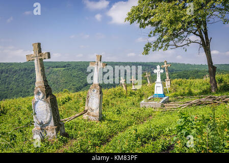 Alte Gräber auf einem verlassenen Friedhof in der Nähe der Burgruine im ehemaligen Dorf Tschervonohorod in der Region Zalischyky, Provinz Ternopil, Ukraine Stockfoto