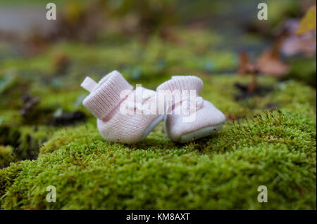 Kleine rosa baby Hausschuhe auf grünem Gras Hintergrund. Baby Schuhe Stockfoto