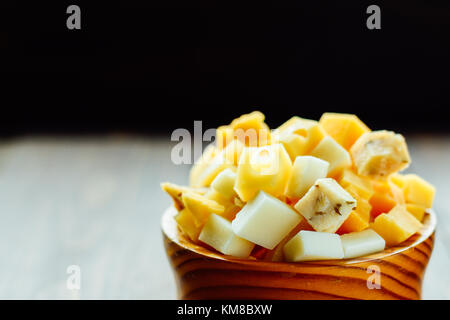 Hölzerne Schüssel mit Stücken von verschiedenen Holland Hartkäse Stockfoto