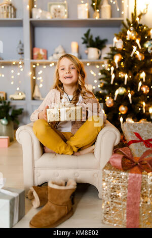 Foto von Mädchen mit Geschenk in den Händen Hintergrund von Christbaumschmuck in Studio Stockfoto