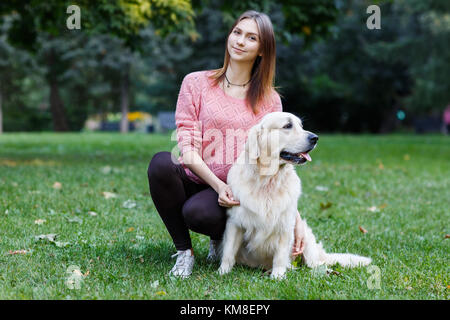 Foto von Mädchen umarmt Hund auf dem grünen Rasen Stockfoto