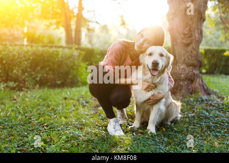 Bild der Frau umarmen Hund auf Rasen Stockfoto