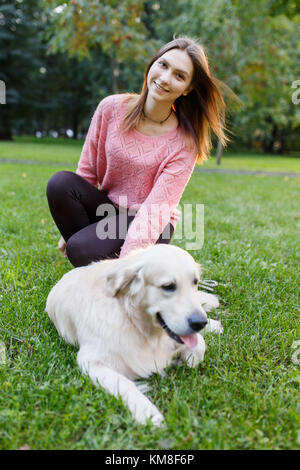 Foto von Mädchen und Retriever liegen auf Rasen Stockfoto