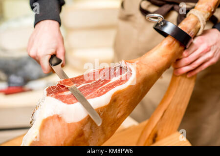 Schneiden mit langen Messer Schinken Bein in der Nahrung Stockfoto