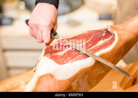 Schneiden mit langen Messer Schinken Bein in der Nahrung Stockfoto