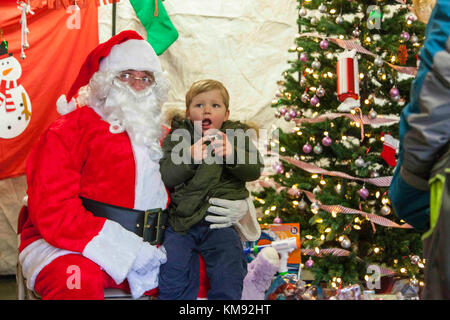 Ein Kind trifft sich mit Santa Clause während des 20. jährlichen Randy Oler Memorial Betrieb Spielzeug Fallen, in Fort Bragg, North Carolina, Dez. 2, 2017. Dieses Jahr, acht Länder beteiligt sind und sie gehören; Kolumbien, Kanada, Lettland, den Niederlanden, Schweden, Italien, Deutschland und Polen. Betrieb Spielzeug Fallen, bewirtet durch die US-Armee die zivilen Angelegenheiten & psychologische Operations Command (Airborne) ist die größte kombinierte Betrieb weltweit durchgeführt. Die Veranstaltung der Soldaten erlaubt, die Möglichkeit, auf ihren militärischen beruflichen Spezialgebiet zu trainieren, pflegen ihre Bereitschaft, in die Luft und zurück auf die l geben Stockfoto