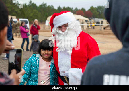 Ein Kind trifft sich mit Santa Clause während des 20. jährlichen Randy Oler Memorial Betrieb Spielzeug Fallen, in Fort Bragg, North Carolina, Dez. 2, 2017. Dieses Jahr, acht Länder beteiligt sind und sie gehören; Kolumbien, Kanada, Lettland, den Niederlanden, Schweden, Italien, Deutschland und Polen. Betrieb Spielzeug Fallen, bewirtet durch die US-Armee die zivilen Angelegenheiten & psychologische Operations Command (Airborne) ist die größte kombinierte Betrieb weltweit durchgeführt. Die Veranstaltung der Soldaten erlaubt, die Möglichkeit, auf ihren militärischen beruflichen Spezialgebiet zu trainieren, pflegen ihre Bereitschaft, in die Luft und zurück auf die l geben Stockfoto