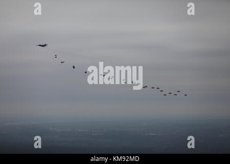 U.S. Army Fallschirmjäger füllen den Himmel, nachdem sie von der C-130 Hercules in der Sicily Drop Zone für die 20. Jährliche Randy Oler Memorial Operation Toy Drop gesprungen sind, die vom U.S. Army Civil Affairs & Psychological Operations Command (Airborne), 02. Dezember 2017 in Fort Bragg, North Carolina, veranstaltet wurde. Die Operation Toy Drop ist die weltweit größte kombinierte Flugoperation mit neun teilnehmenden Fallschirmjägern der Partnernation und ermöglicht es Soldaten, ihre militärischen Berufsspezialitäten zu trainieren, ihre Flugbereitschaft aufrechtzuerhalten und der lokalen Gemeinschaft etwas zurückzugeben. Stockfoto