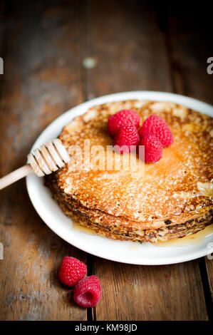 Pfannkuchen mit Ahornsirup und Himbeeren auf hölzernen Hintergrund Stockfoto