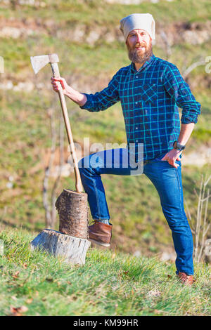 Junge Holzhacker mit Bart hält seine Axt in der Hand. Stockfoto