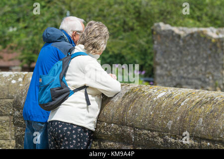 Paar mittleren Alters stehen zusammen über eine alte Brücke in Großbritannien suchen. Stockfoto
