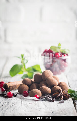 Hausgemachte gesunde vegane Schokolade Trüffel mit Cranberry auf Papier über weiß Holz- Hintergrund Stockfoto