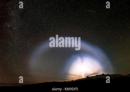 Ein buntes Panorama der Sternenhimmel mit Sternen und einem schönen ungewöhnliche Halo aus dem Ufo in den nächtlichen Himmel über den Bergen Stockfoto