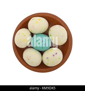Easter egg Malz ball Bonbons in einem kleinen roten Ton Schüssel mit einem blauen Candy von weißen Bonbons auf weißem Hintergrund umgeben. Stockfoto