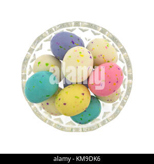 Blick von oben auf einige gesprenkelte Osterei Malz ball Bonbons in eine Glasschüssel auf einem weißen Hintergrund. Stockfoto