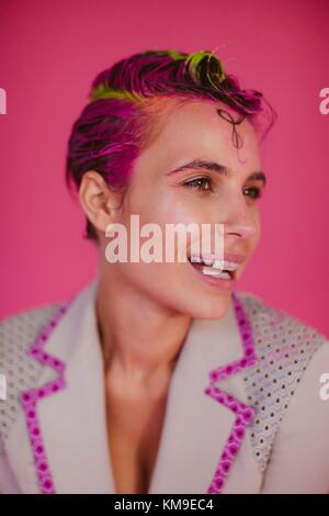 Porträt einer lächelnde Frau mit rosa Haaren und Klammern Stockfoto
