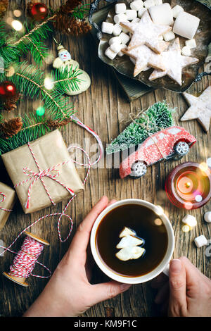 Woman's Hand, die Tasse Kaffee mit einem Weihnachtsbaum geformte Marshmallow Stockfoto