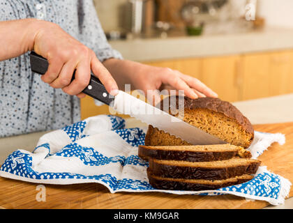 Frau schneiden Scheiben glutenfreies Brot Stockfoto