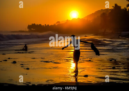 Silhouette der Boy entlang Sonnenuntergang Sunbeam auf tropischen Strand auf El Salvador Küste Stockfoto