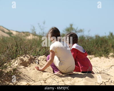 2 Girls spielen mit dem Sand auf einer Sanddüne Stockfoto