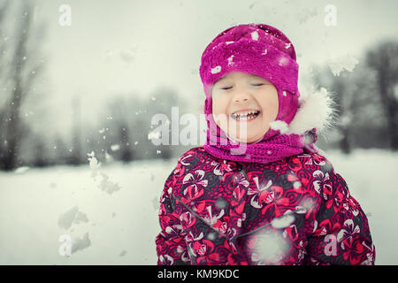 Kid spielen mit Schneeflocken im Winter Wald Stockfoto
