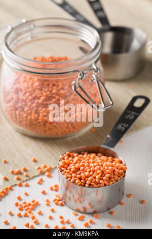 Rohe rote, getrocknete Linsen Messung Lufthutze aus Metall und Glas storage Jar am Küchentisch Stockfoto