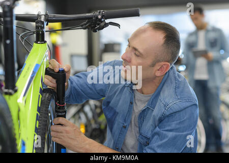 Man prüft Fahrrad vor dem Kauf im Sportgeschäft Stockfoto