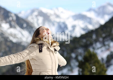 Porträt einer Frau, die aufgeregt im Winter Lachen mit einem schneebedeckten Berg im Hintergrund Stockfoto