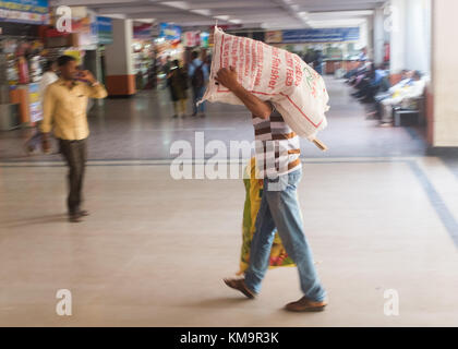 Mann Tragen von schweren Sack in Bus Station, Mysore, Karnataka, Indien. Stockfoto