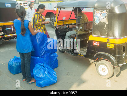 Zwei Frauen mit viel Gepäck zahlen auto Rikscha Fahrer ausserhalb Busbahnhof in Mysore, mysuru, Karnataka, Indien. Stockfoto