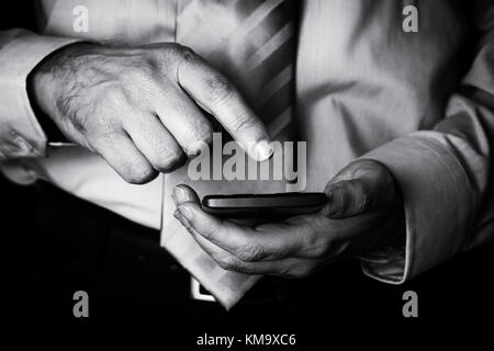 Mann hält und berührt, Bildschirm oder Display mit Finger von einem Mobiltelefon, Handy oder Smartphone. männliche Unternehmer eine Meldung eingeben oder im Internet surfen Stockfoto