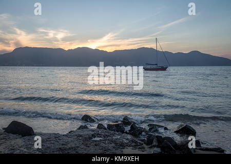 Segelboot bei Sonnenuntergang mit Sao Sebastiao auf Hintergrund - ilhabela, Sao Paulo, Brasilien Stockfoto