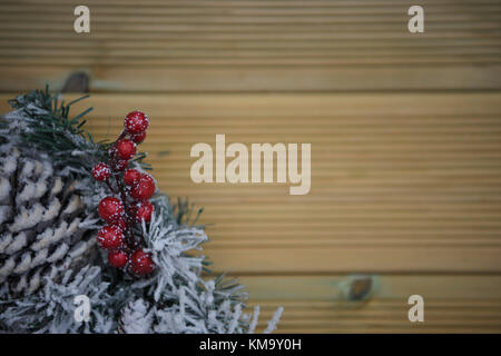 Weihnachten fotografie Bild eines Green Pine Tree Kranz im Schnee mit roten Beeren und rustikal Naturholz Hintergrund Stockfoto