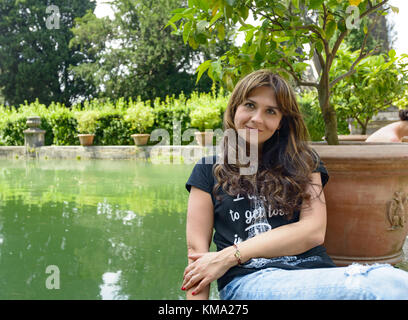 Nettes Mädchen mit langen Haaren in der Nähe von einem künstlichen See und ein Lemon Tree in Rom Stadtteil e.u.r. Posing Stockfoto