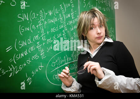 Überrascht Lehrer vor dem Hintergrund einer grünen Tafel Stockfoto