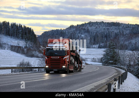 Salo, Finnland - Dezember 2, 2017: rote Scania R480 Car carrier Hols neues Auto in der Dämmerung entlang der Autobahn im Winter. Stockfoto