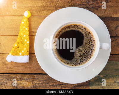 Espresso in Schale mit gelben santa hut auf Holz Tisch. Stockfoto