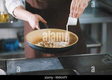 Koch ist Gießen die Soße in das Fleisch Stockfoto