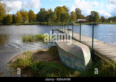 Invertiert Bügeleisen Boot und hölzernen Pier auf dem Fluss mit Herbst gelb Bäume vor dem Hintergrund Stockfoto