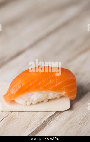 Ein Lachs nigiri Sushi in einem hölzernen Paletten, auf einem rustikalen Holztisch, mit einem leeren Raum auf der Oberseite Stockfoto