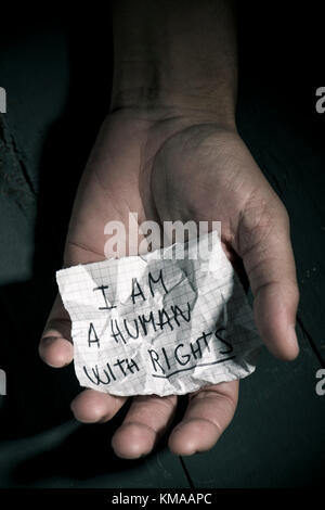 Nahaufnahme der Hand eines jungen Mannes mit einem Ein Stück Papier mit dem Text Ich bin ein Mensch Mit den darin geschriebenen Rechten Stockfoto