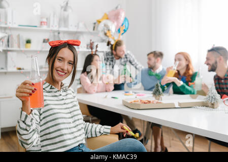 Süße Mitarbeiter Schiebeschalter an Office Party mit Kollegen im Hintergrund Stockfoto