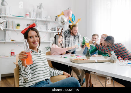 Mitarbeiter mit einem Cocktail bei einem Urlaub office Party mit Kollegen Schiebeschalter im Hintergrund Stockfoto