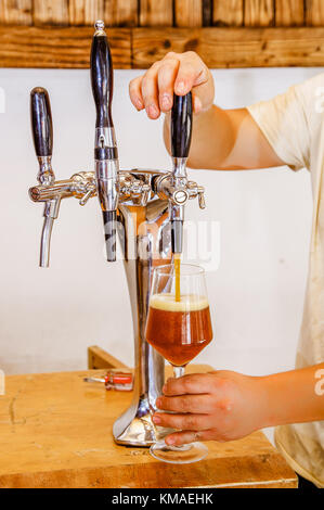 Barkeeper Hand am Bier gießt ein Fass Bier in einem Restaurant oder Pub serviert, in einem verschwommenen Hintergrund Stockfoto