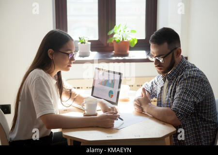 Zwei tausendjährige Kollegen diskutieren die Probleme auf die Unternehmen treffen im Büro. Geschäftsfrau, Geschäftsmann, ein Dokument mit Job Frage Stockfoto